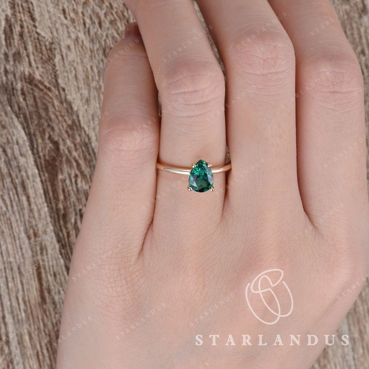 a woman's hand with a gold ring and a green gemstone stone on it