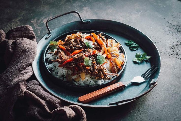 a plate with rice, meat and vegetables on it next to a knife and fork