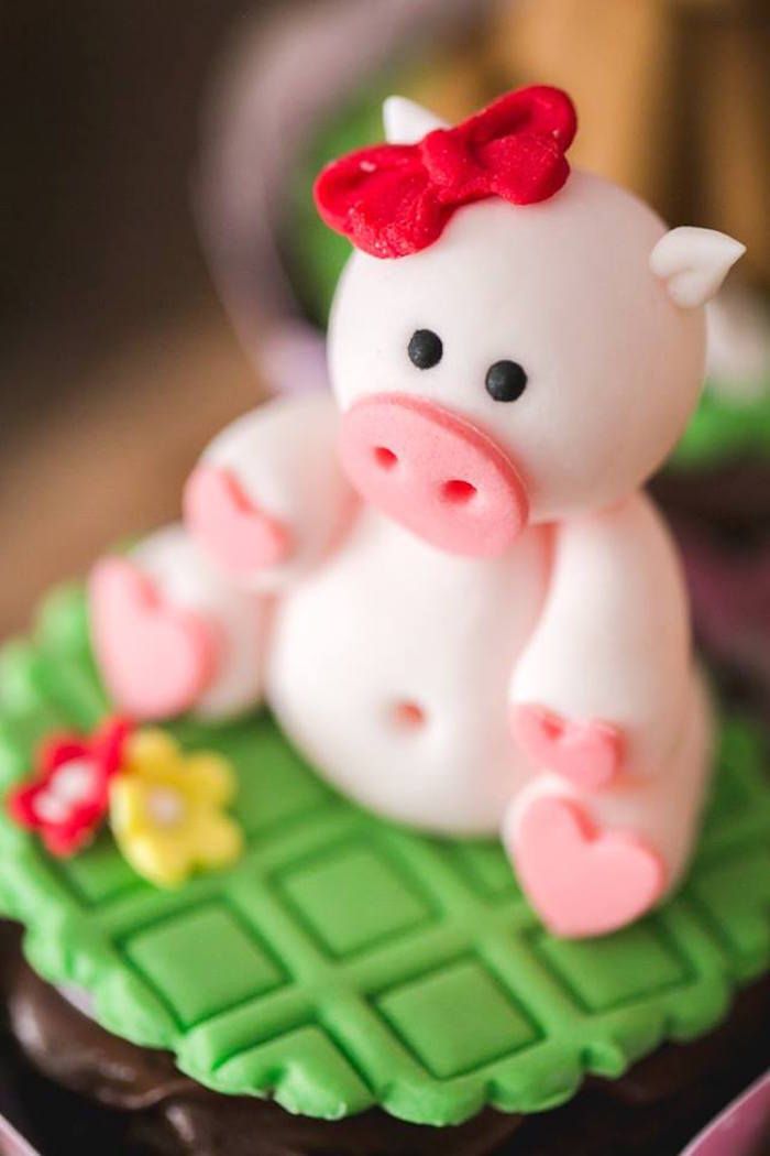 a cupcake decorated like a pig with a red bow on it's head