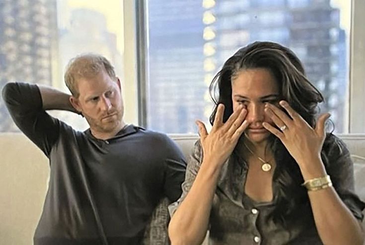 a man and woman sitting on a couch with their hands covering their eyes as they look at each other