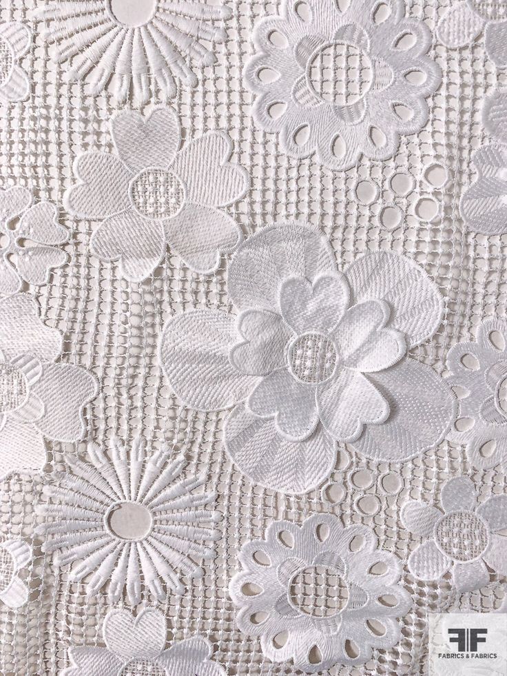 the back side of a white lace fabric with flowers and leaves on it's edges