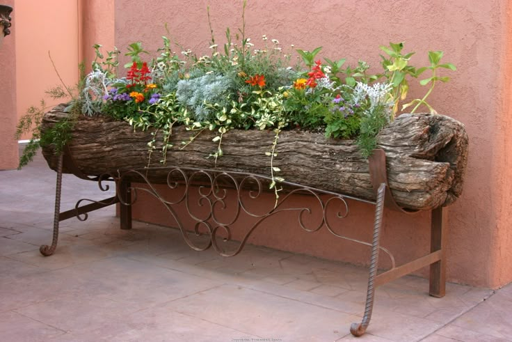 a wooden bench with flowers and plants in it