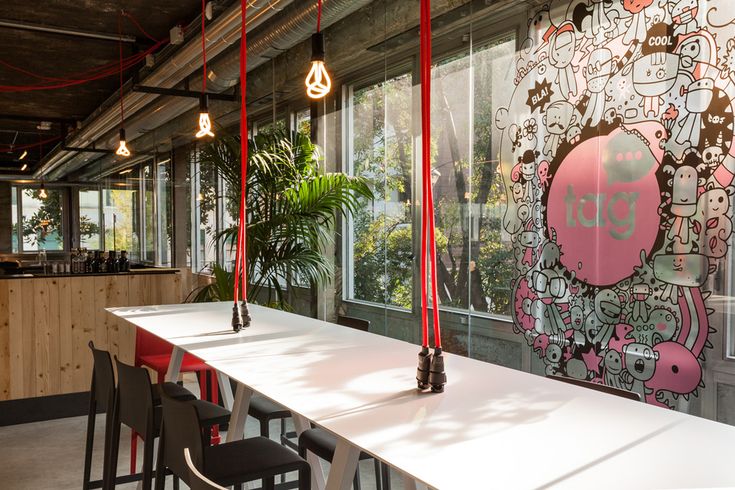 a long table with chairs in front of a large window and graffiti on the wall