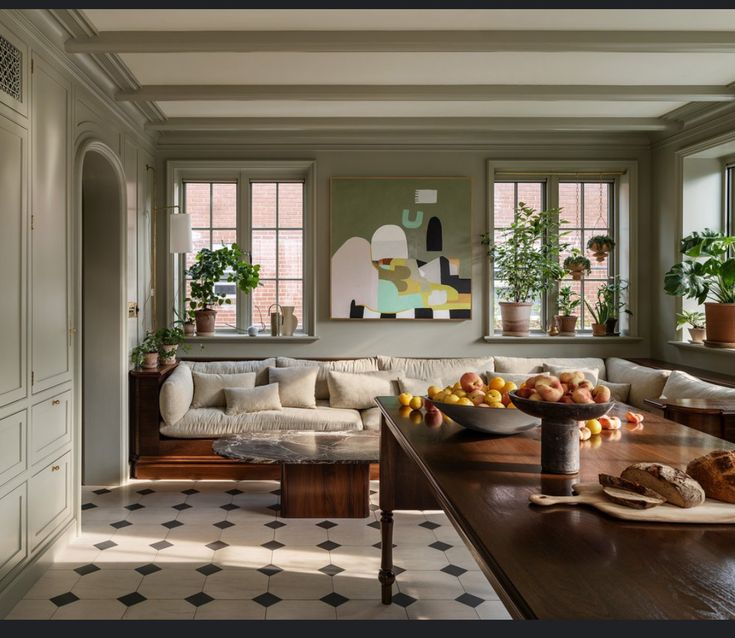 a living room filled with furniture and lots of windows next to a wooden dining table