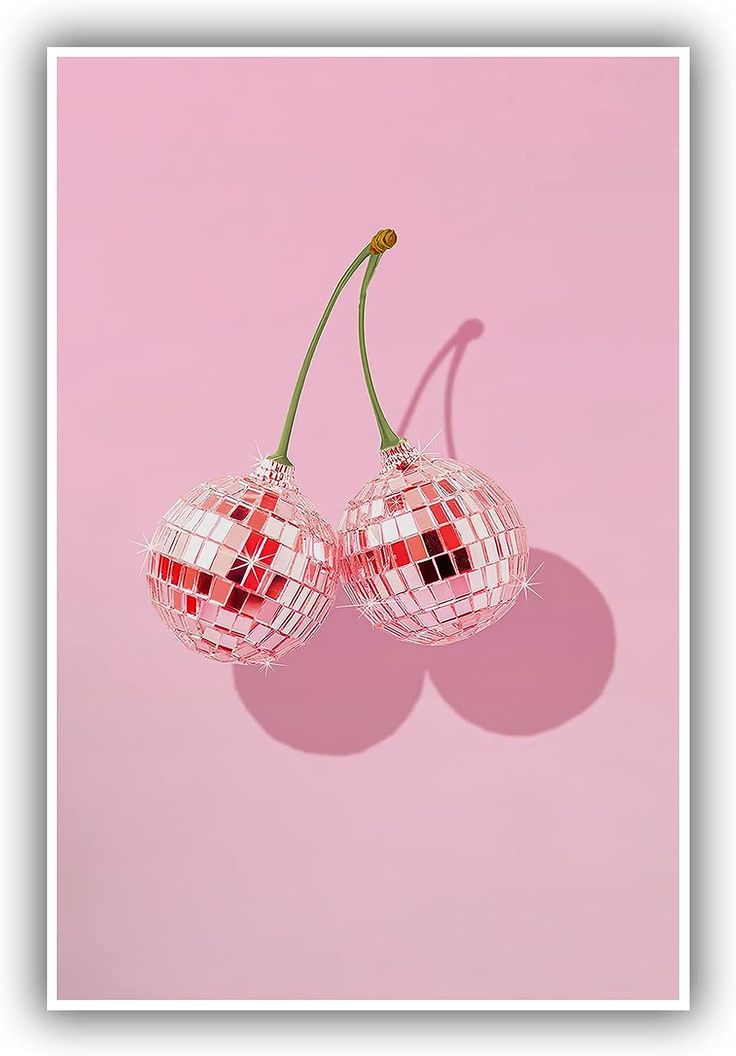 two red and white glass cherries on a pink background