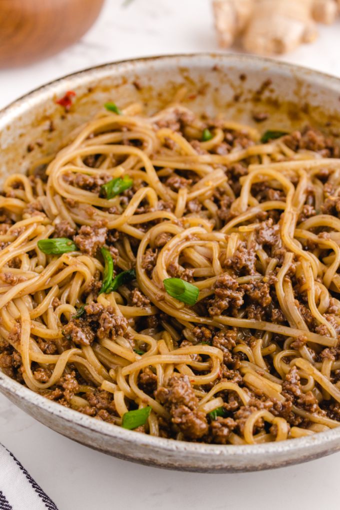 a pan full of spaghetti with meat and parsley on the side, ready to be eaten