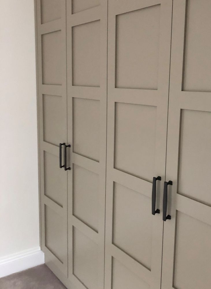 an empty room with some white cupboards and doors on the wall, in front of a carpeted floor