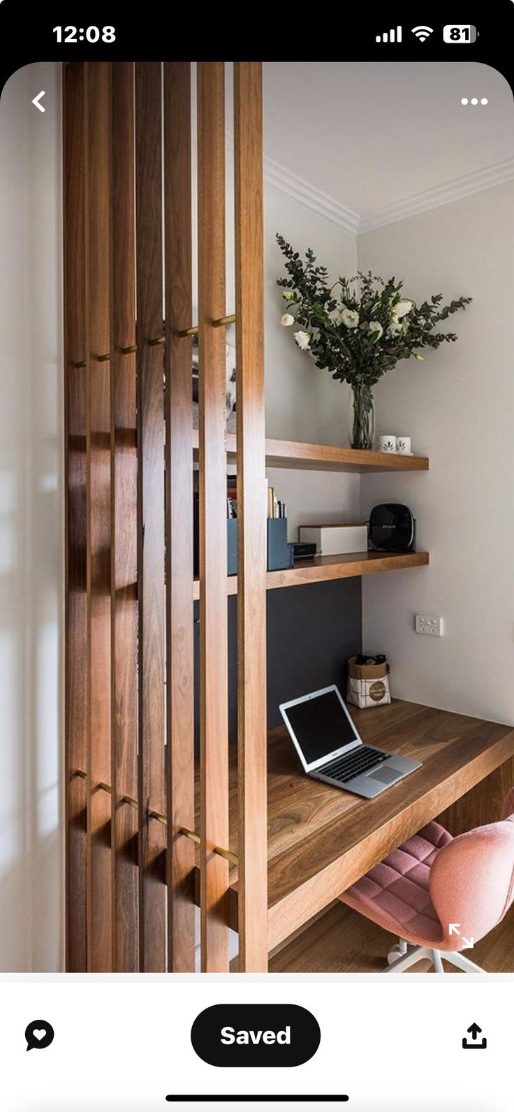 a laptop computer sitting on top of a wooden desk next to a plant and bookshelf