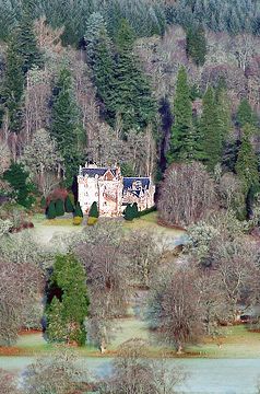 an aerial view of a house in the middle of some trees and land with water running through it