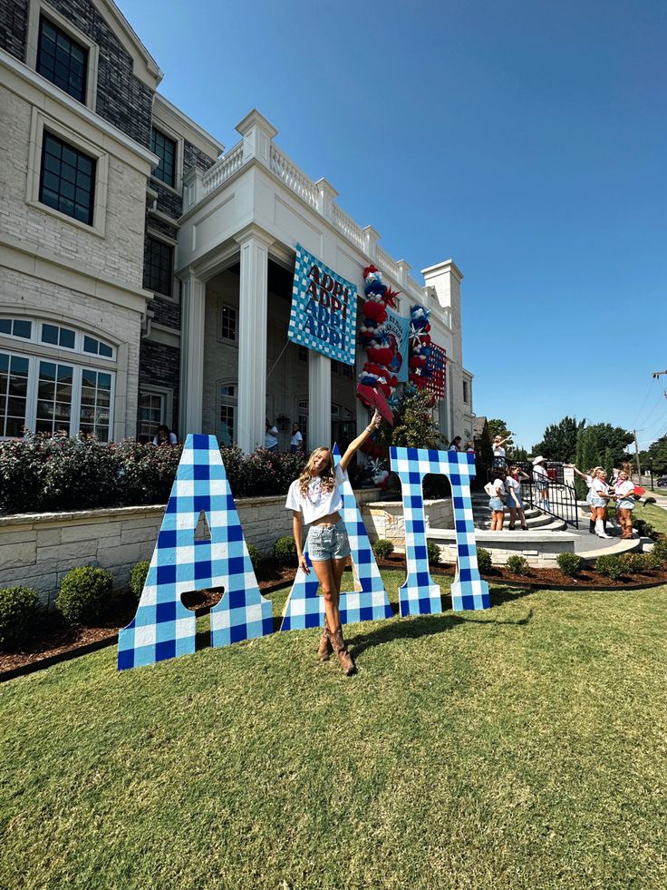 a woman is standing in front of a giant letter