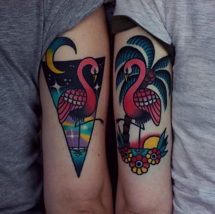 two flamingos are on the arms of each other