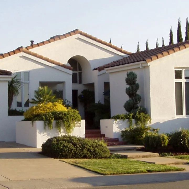 a white house with trees and bushes in front