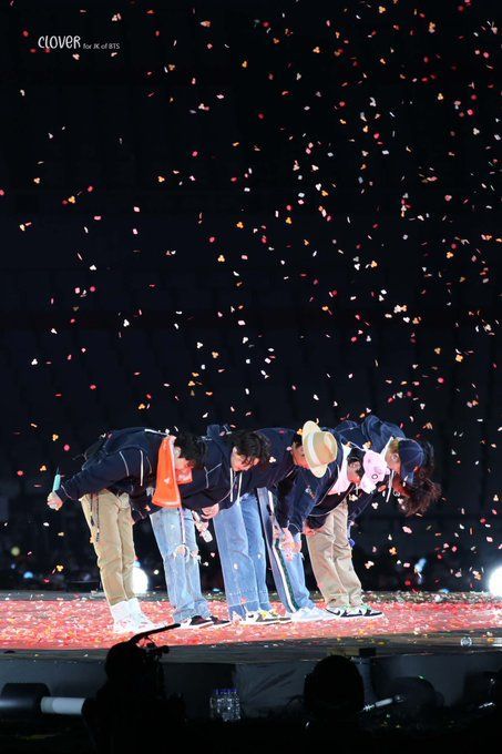 three men standing on top of a stage with confetti falling from the sky