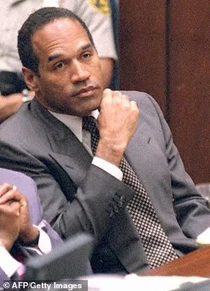 a man in a suit and tie sitting at a table with other people behind him