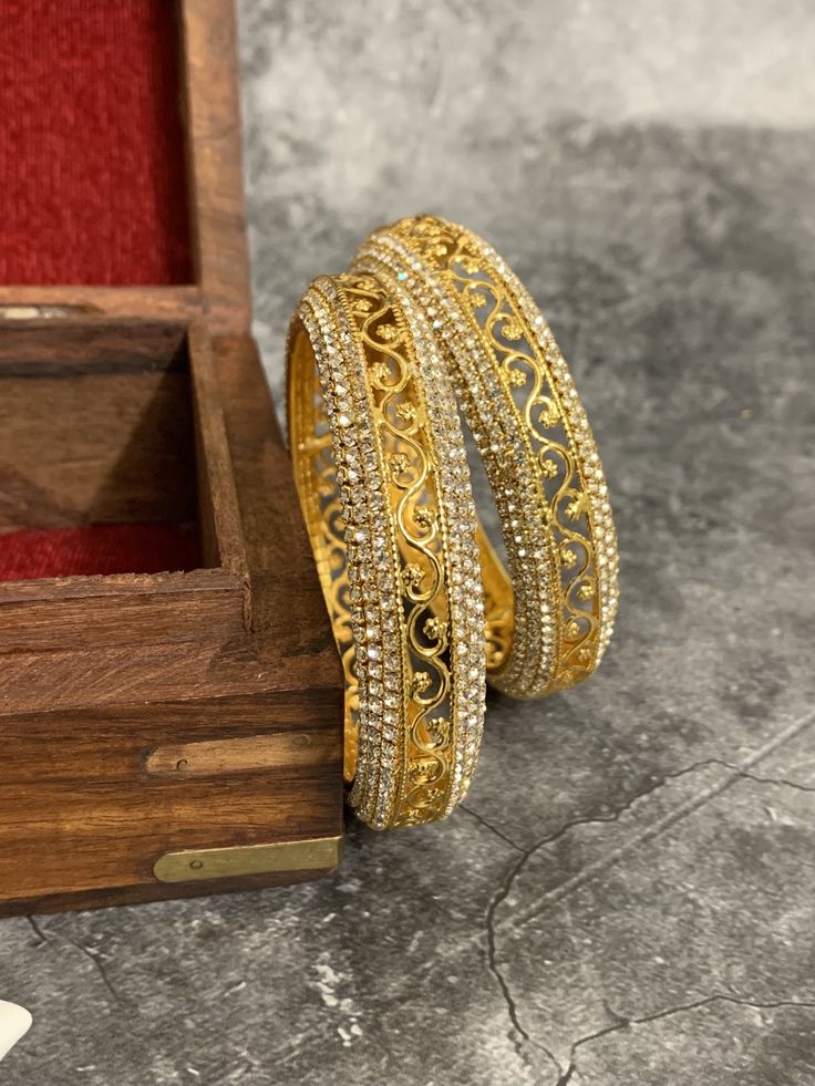 Gold plated bangle set Aruna . Comes in pair.Silver Rhinestone work around . Silver Bangle With Stone Setting For Festive Occasions, Festive Silver Bangle With Stone Setting, Festive American Diamond Bangle With Intricate Design, Traditional Silver Bangle With Stone Setting, Metal Round Bangle For Wedding, Traditional Gold Bangle With American Diamond, Gold Bling Bangle Gift, Metal Bangle For Weddings, Festive Round Jewelry With Rhinestones