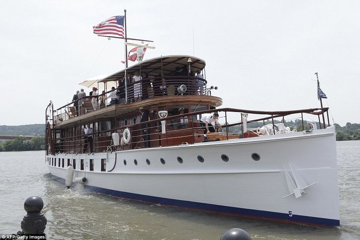 a large white boat floating on top of a lake next to a dock with an american flag