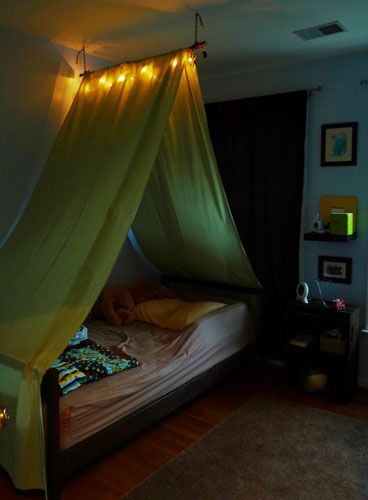 a canopy bed with lights hanging from it's sides