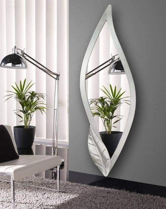 a mirror hanging on the side of a wall next to a table with a potted plant