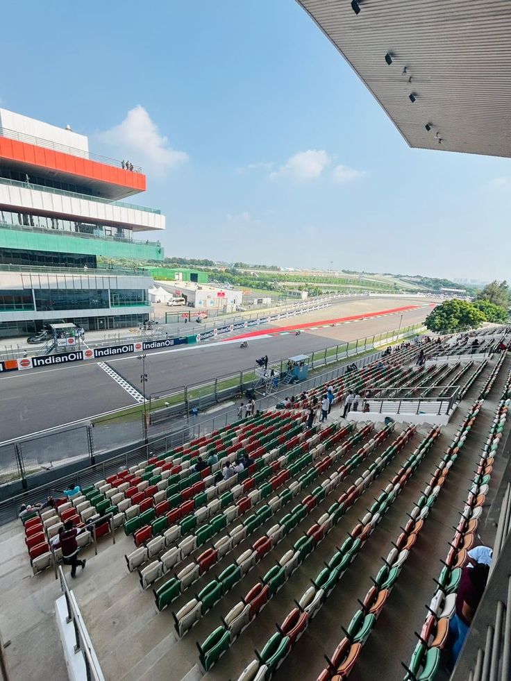 an empty race track filled with lots of green and red seats next to a tall building