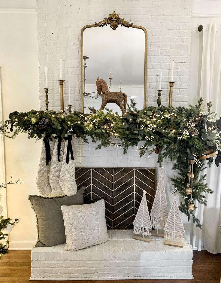 a fireplace decorated for christmas with stockings and evergreen garland on the mantel above it