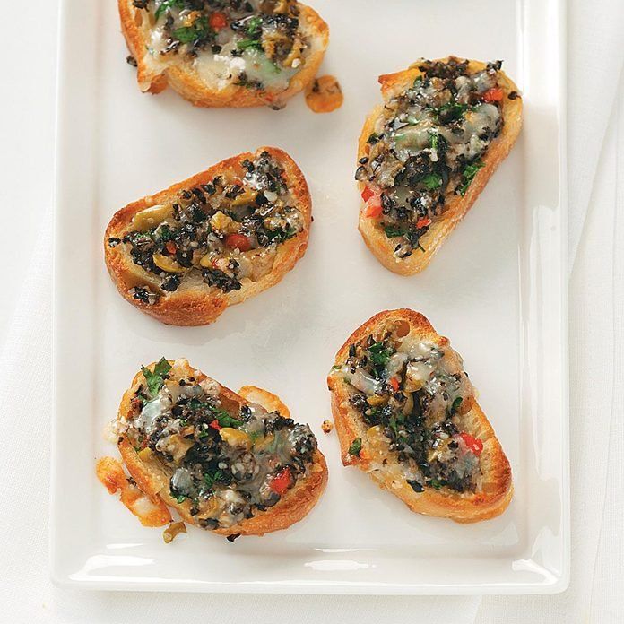 four pieces of toasted bread with various toppings on them sitting on a white plate