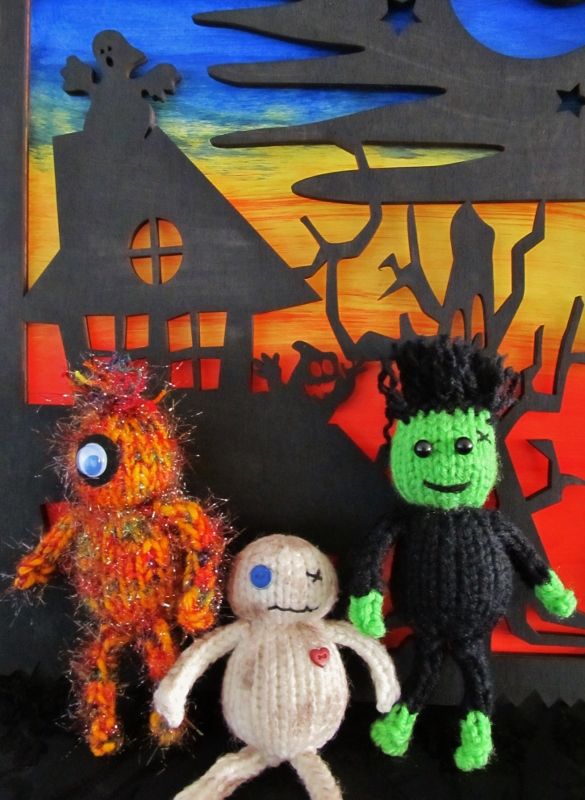 two knitted dolls are standing next to each other in front of a halloween scene