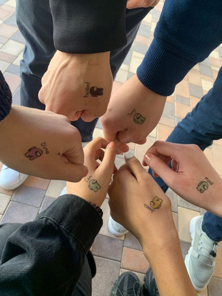 four people holding hands with small tattoos on their wrists and fingers in a circle together