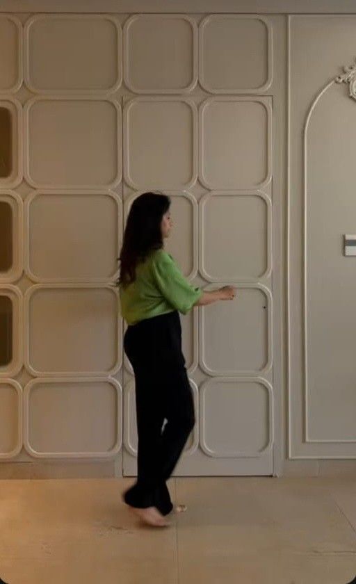 a woman standing in front of a white wall with a cross on it's side