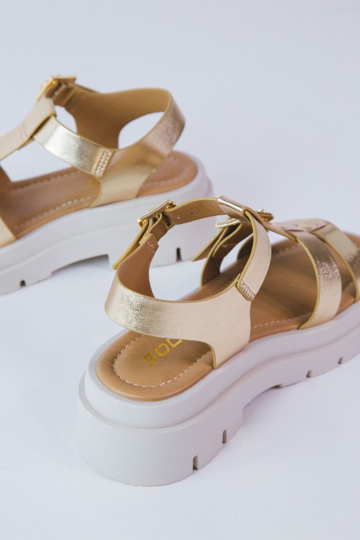 Elevate your summer style game with the Dilia Lug Sole Sandal in Metallic Gold. Featuring double buckle and adjustable straps, these sandals offer a secure and comfortable fit. The platform and square toe add a trendy touch. Walk with confidence and shine on in these stylish sandals! General Info: Man Made Materials Double Buckle Adjustable Straps Metallic Gold 1-2" Platform Square Toe Imported Walk With Confidence, Stylish Sandals, Lug Sole, Clothing Company, Metallic Gold, Summer Style, Gold Metal, Adjustable Straps, Comfort Fit