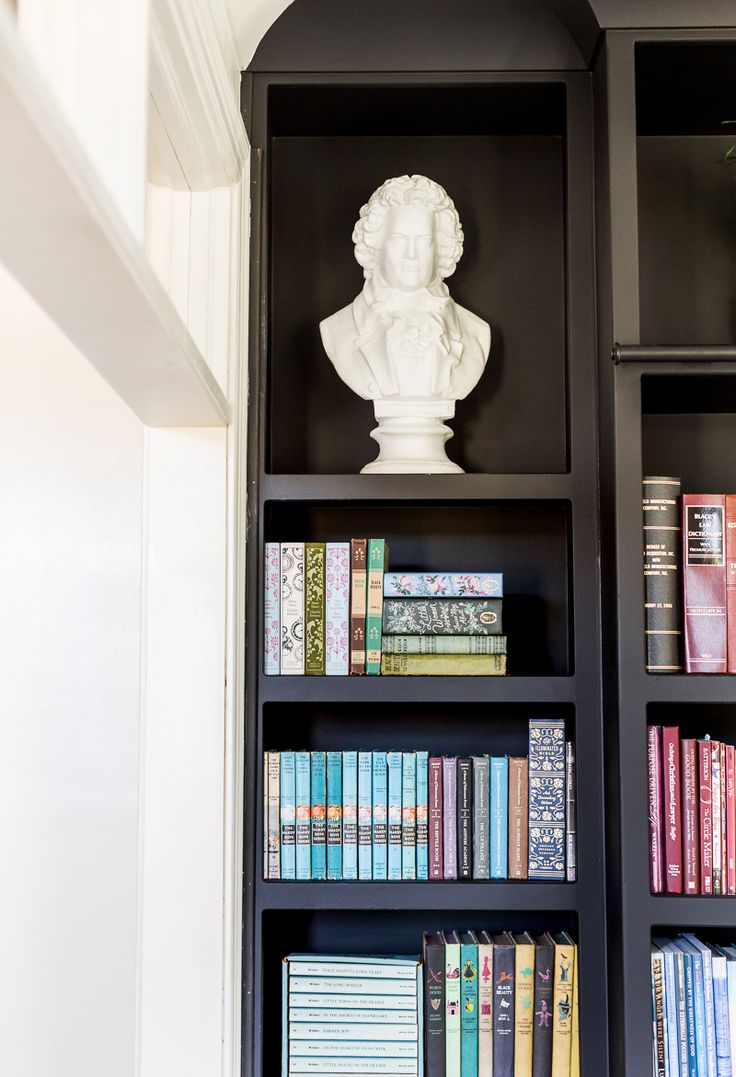 a bookshelf filled with lots of books next to a white busturine