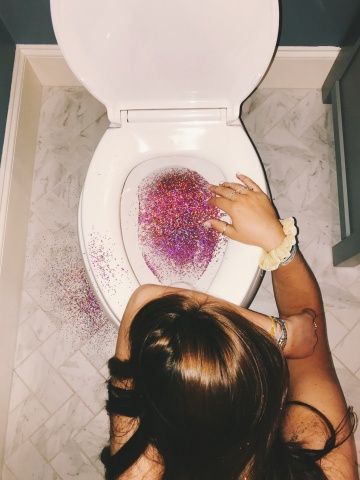 a woman is sitting on the toilet with her hands in the bowl and sprinkles all over it