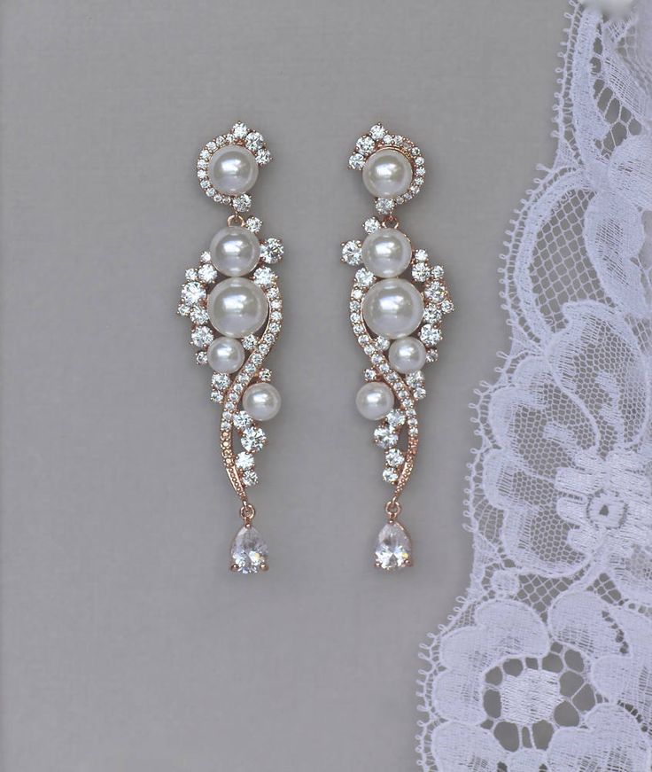 two pairs of pearl and crystal earrings on top of a lace doily with white lace