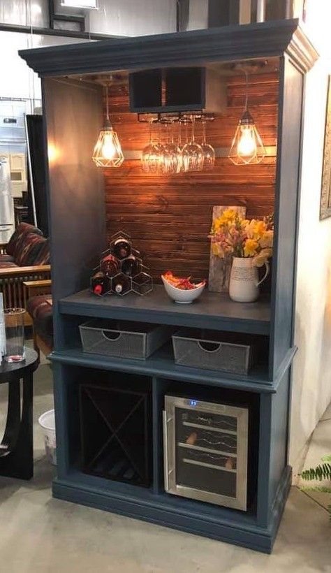 an entertainment center with wine glasses on the top shelf and two baskets under the shelves