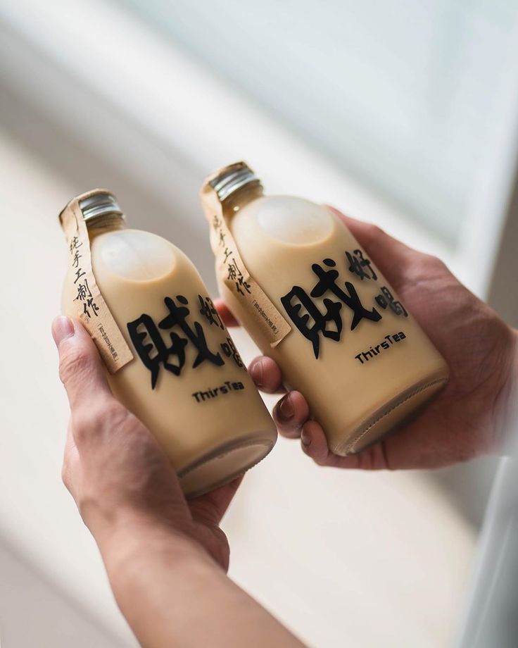 two people holding up bottles with writing on them