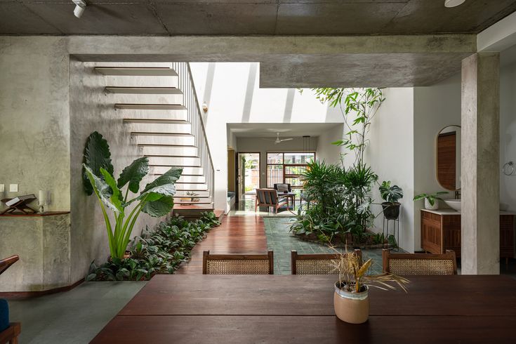 a dining room table with chairs and plants in the center, next to a stair case