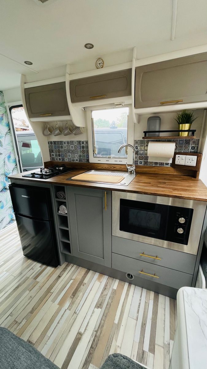 a kitchen area with sink, stove and counter top in a recreational vehicle or camper