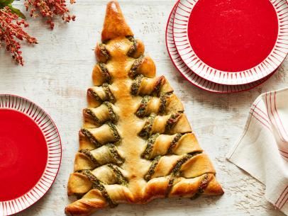 a christmas tree shaped pastry sitting on top of a white table next to red plates