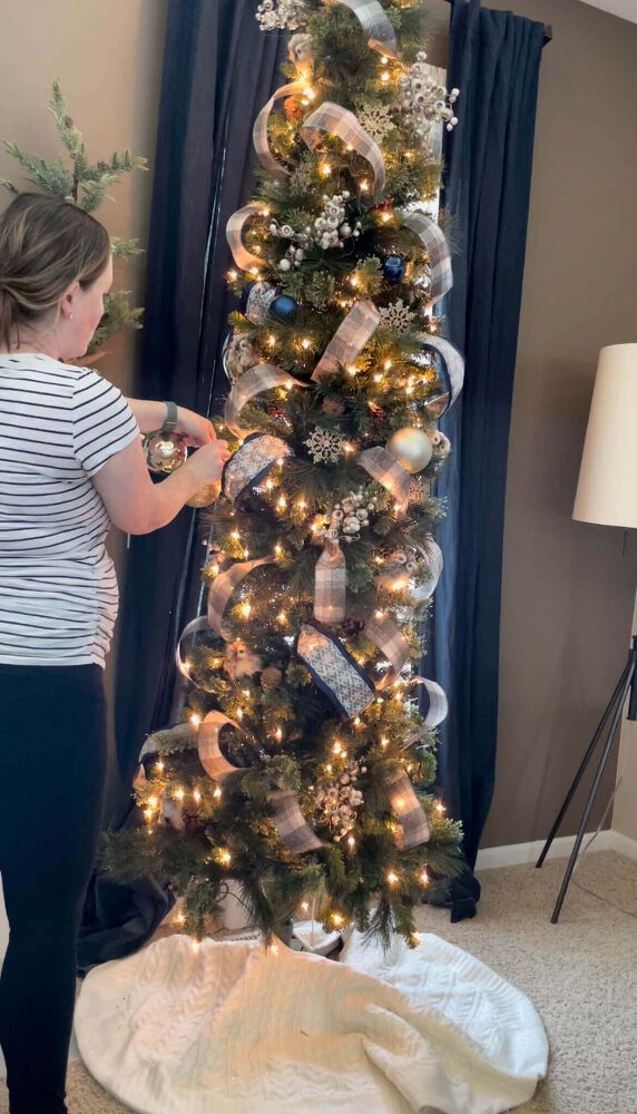 a woman decorating a christmas tree in her living room