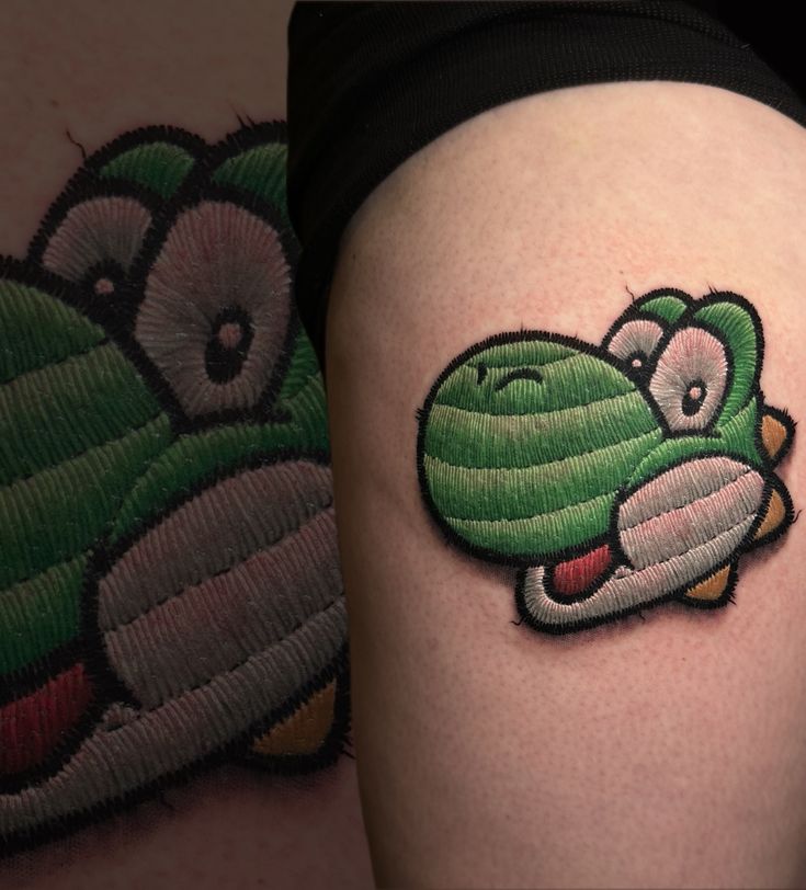 a green cartoon character tattoo on the thigh