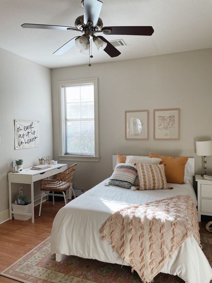 a bedroom with a bed, desk and ceiling fan