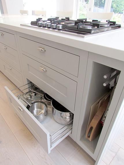 an open drawer in a kitchen with pots and pans on the counter top,