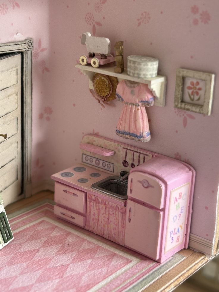 a doll house kitchen with pink furniture and accessories on the walls, including a stove top oven