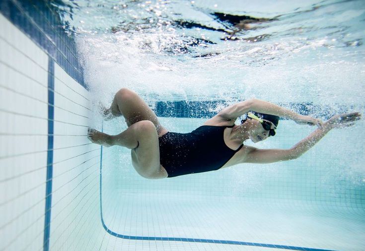 a woman in a black swimsuit swimming under water