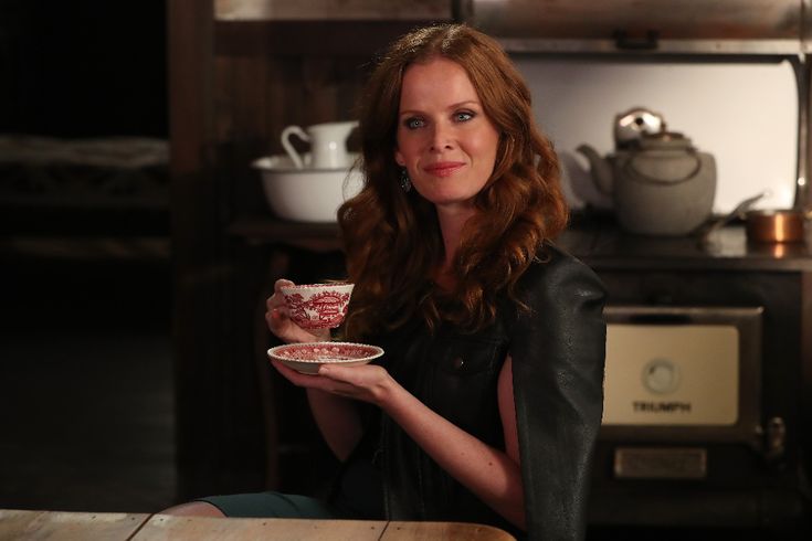 a woman sitting at a table with a plate in her hand and looking into the camera