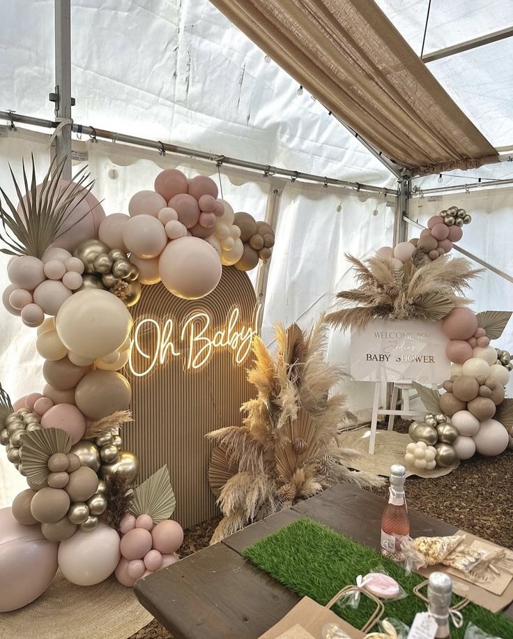 a table topped with lots of balloons and greenery next to a sign that says oh baby