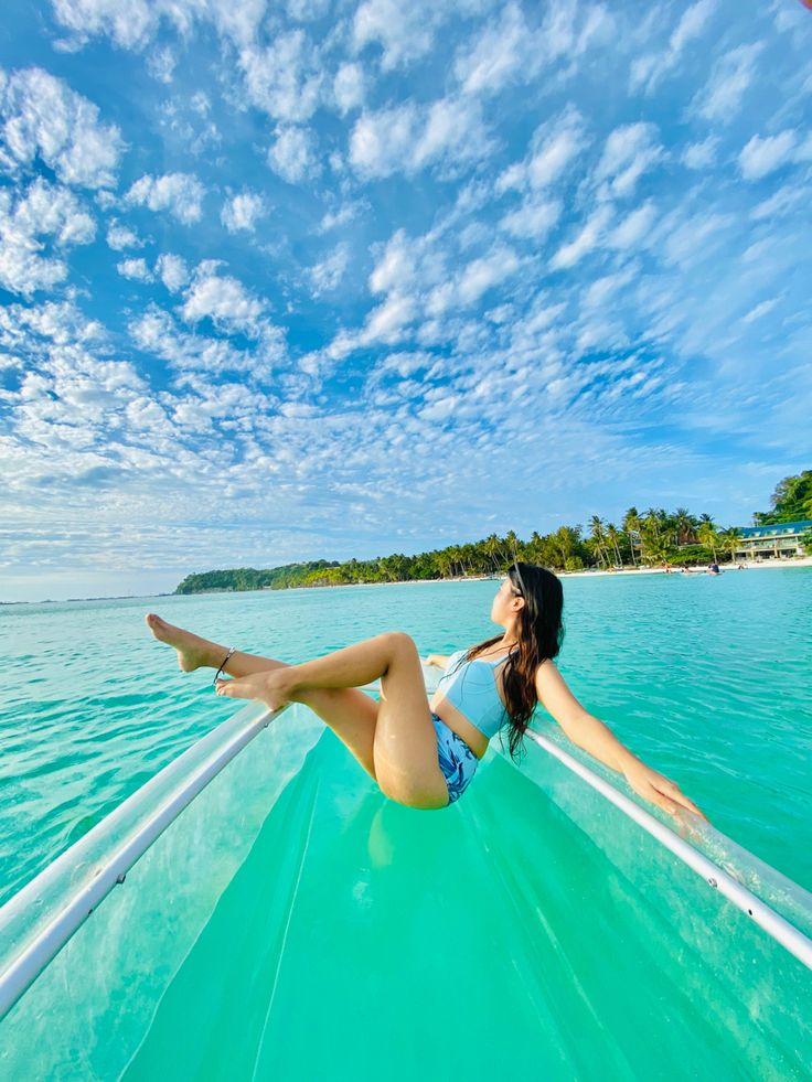 a woman is laying down on the back of a boat in the water with her legs spread out