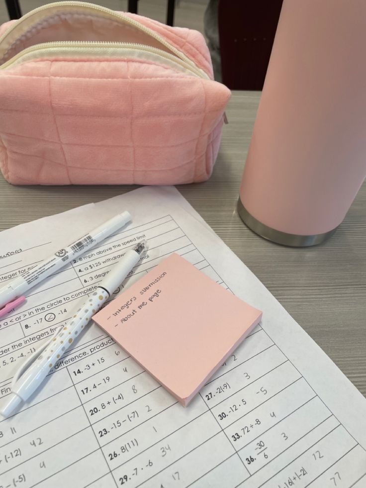 a pink purse sitting on top of a desk next to a pen