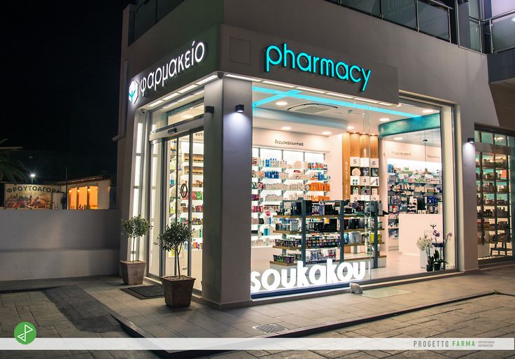 a pharmacy store front at night with its lights on and shelves full of medicine products