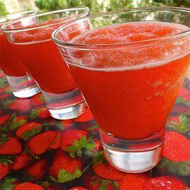 three glasses filled with red liquid sitting on top of a table next to each other