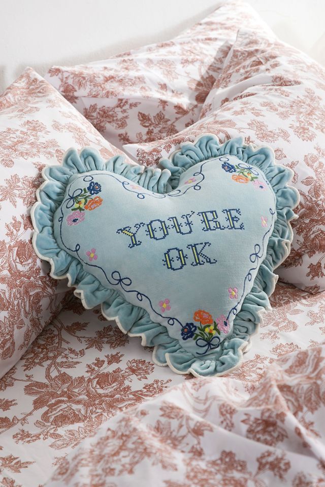 a heart shaped pillow sitting on top of a bed